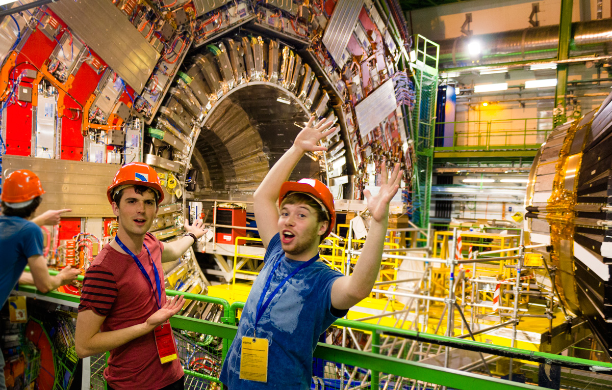 Founders of ScienceNation, Sean Cooper and George Percival, photographed infront of the CMS detector at CERN. They are posing in quite a humorous manner.